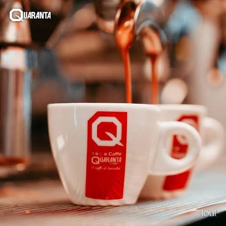 Filxhan i bardhë porcelani me logon Quaranta Caffe, ndërsa rrjedh kafeja espresso